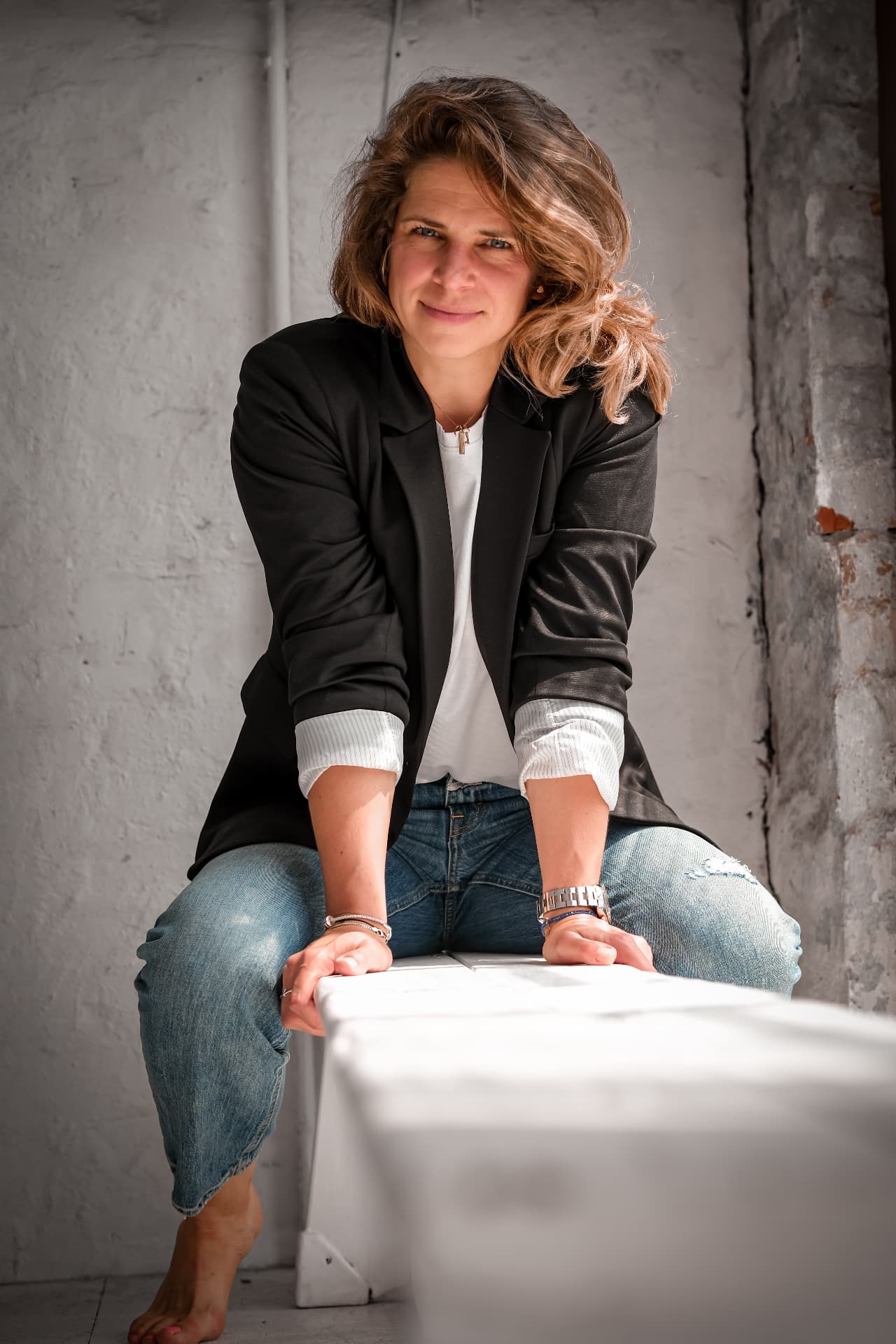 Sina sitzend in Blazer und Jeans